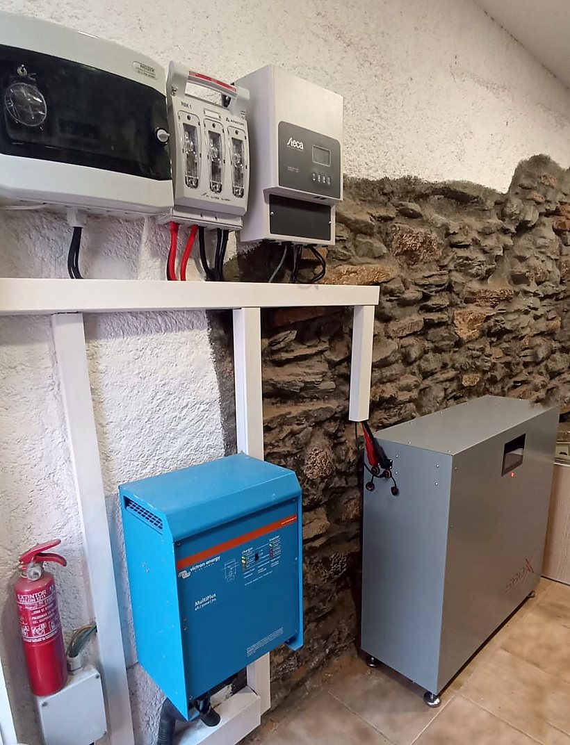 Bateria SolarBox de 30 kWh afegida a una instal·lació solar que ja existia: armari contra una paret de pedra, amb l'inversor Victron MultiPlus de 4 kW, el regulador solar Steca i la caixa de proteccions